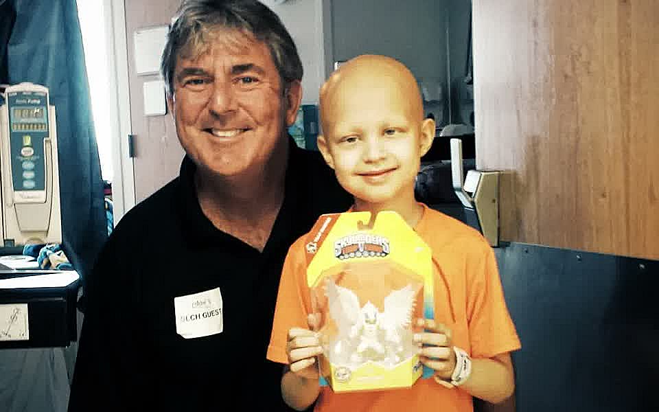 A GameChanger volunteer and a beaming young patient with a new gift in the hospital.