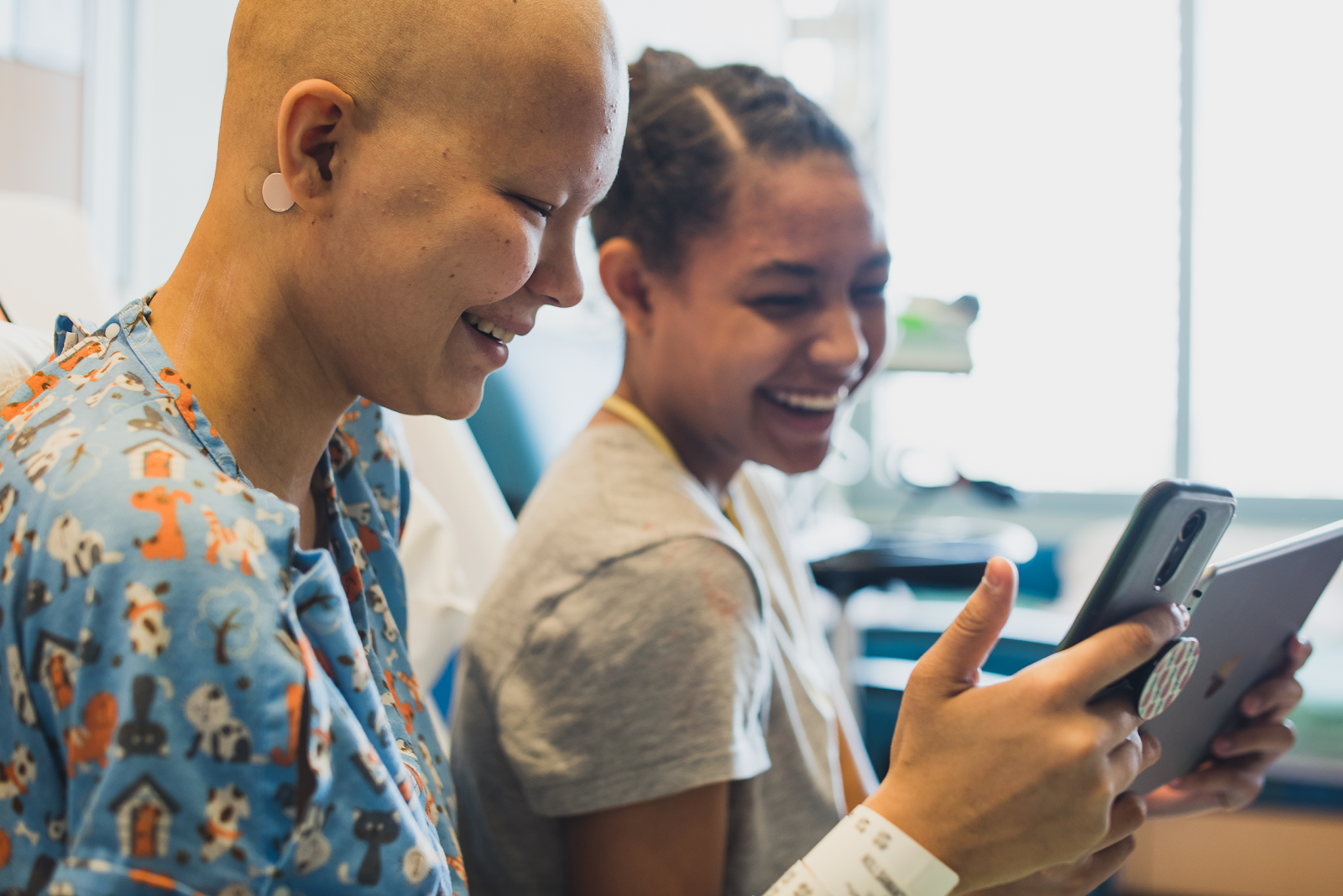 Two young patients playing on a tablet together.